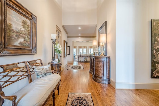 corridor featuring light wood-type flooring, a towering ceiling, baseboards, and recessed lighting