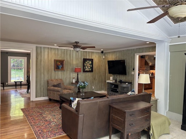 living room with a ceiling fan, ornamental molding, ornate columns, wood finished floors, and baseboards