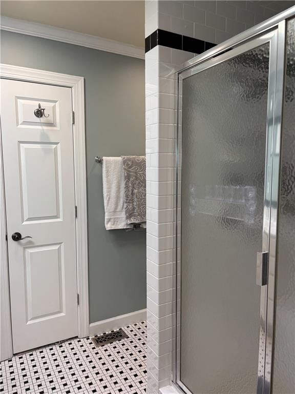 full bath featuring crown molding, a stall shower, baseboards, and tile patterned floors