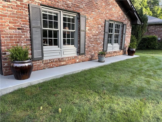 view of exterior entry with brick siding and a lawn