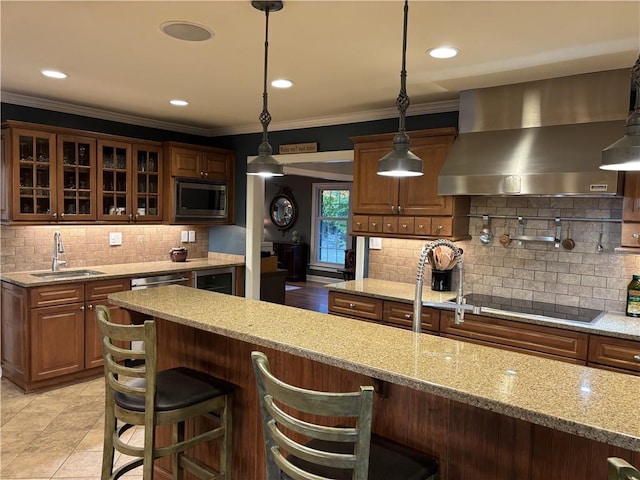 kitchen with wall chimney exhaust hood, stainless steel microwave, a sink, black electric cooktop, and decorative backsplash