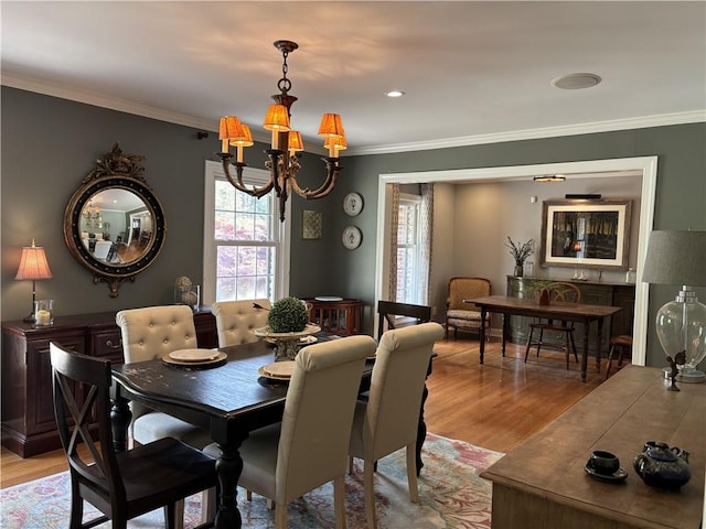 dining area with a chandelier, light wood finished floors, and ornamental molding
