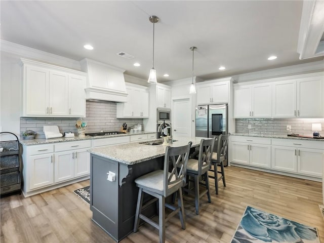 kitchen with sink, appliances with stainless steel finishes, pendant lighting, and white cabinets