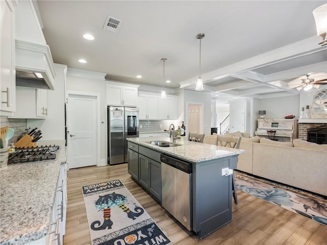 kitchen featuring wood-type flooring, sink, stainless steel appliances, white cabinets, and a center island with sink