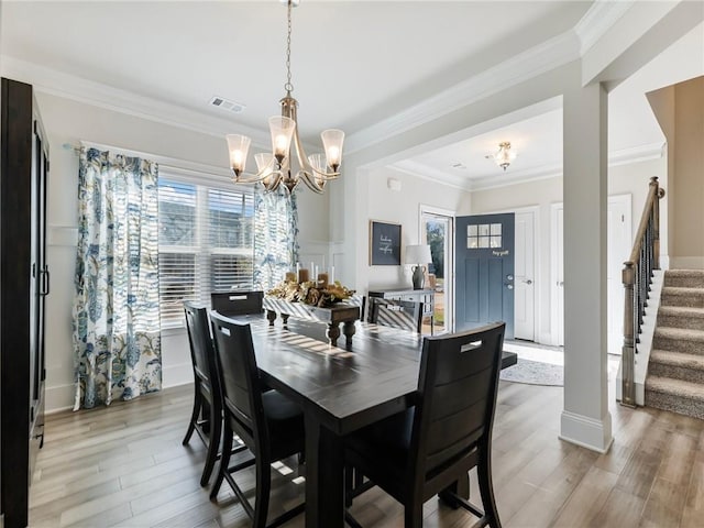 dining space with ornamental molding, light hardwood / wood-style flooring, and an inviting chandelier