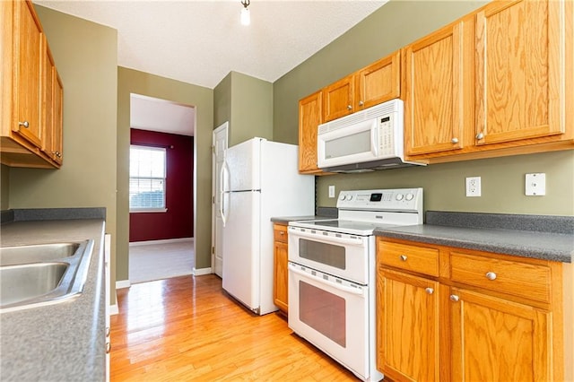 kitchen featuring sink, white appliances, and light wood-type flooring