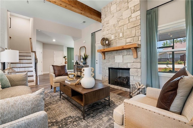 living room featuring beamed ceiling, a stone fireplace, and dark hardwood / wood-style flooring