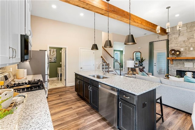 kitchen featuring sink, white cabinetry, hanging light fixtures, stainless steel appliances, and a fireplace