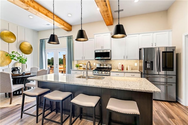 kitchen with appliances with stainless steel finishes, sink, white cabinets, light stone counters, and french doors