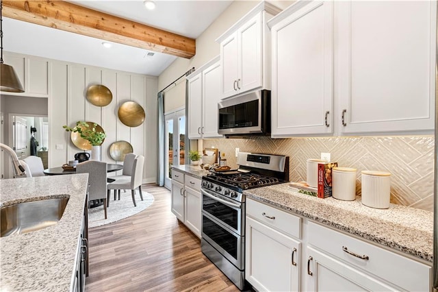 kitchen featuring sink, white cabinetry, stainless steel appliances, light stone countertops, and backsplash