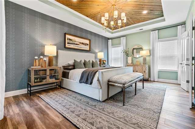 bedroom with a raised ceiling, hardwood / wood-style floors, wooden ceiling, and an inviting chandelier