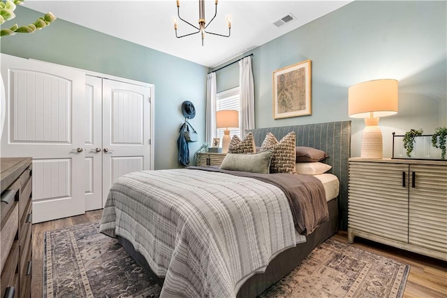 bedroom with an inviting chandelier, hardwood / wood-style floors, and a closet