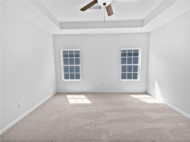 carpeted spare room with a tray ceiling and ceiling fan