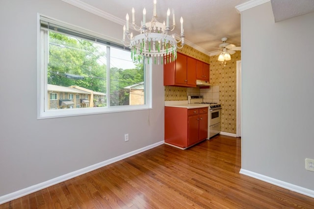 kitchen with white gas range, wood finished floors, baseboards, and crown molding