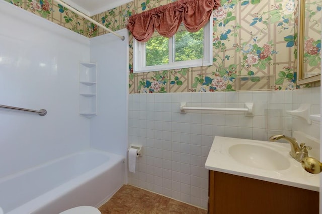 full bath with tile walls, wallpapered walls, wainscoting, vanity, and bathing tub / shower combination