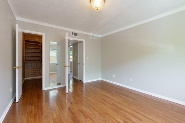 unfurnished room with crown molding, baseboards, visible vents, and wood finished floors