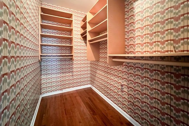 interior space with wallpapered walls, wood finished floors, and baseboards