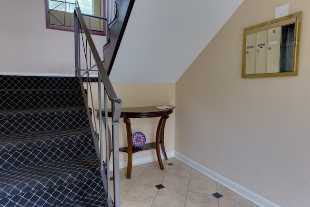stairway featuring baseboards, tile patterned flooring, and lofted ceiling