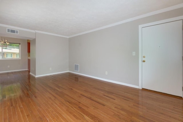 spare room with visible vents, baseboards, ornamental molding, and hardwood / wood-style flooring