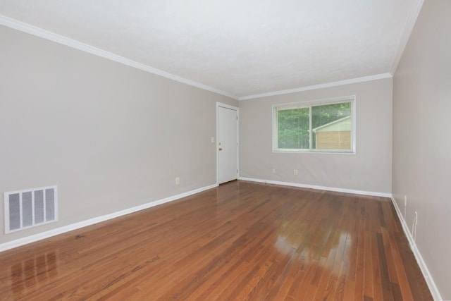 empty room featuring baseboards, hardwood / wood-style floors, ornamental molding, and visible vents