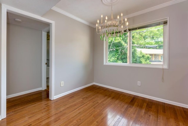 spare room with baseboards, ornamental molding, light wood finished floors, and an inviting chandelier