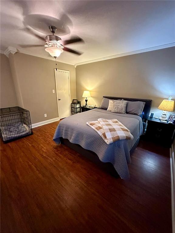 bedroom with dark hardwood / wood-style flooring, ceiling fan, and crown molding