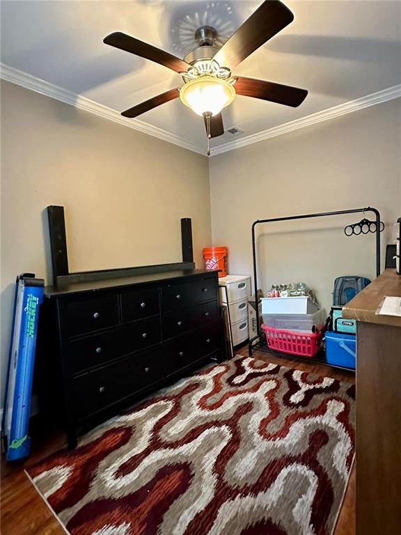 bedroom featuring dark hardwood / wood-style flooring, ceiling fan, and crown molding