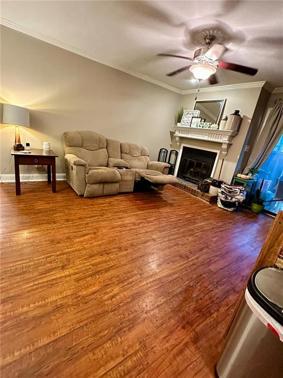 living room with wood-type flooring, ceiling fan, and ornamental molding