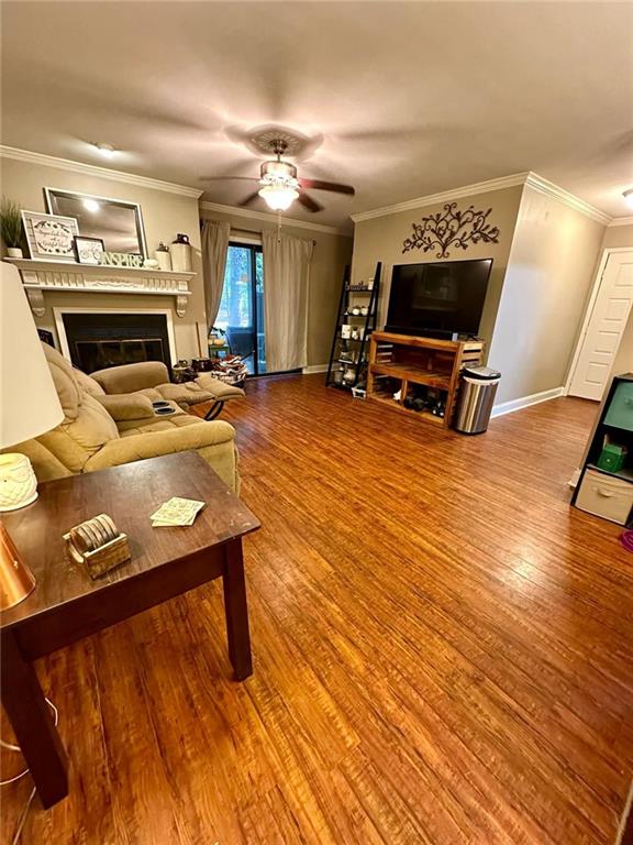 living room featuring hardwood / wood-style floors, ceiling fan, and crown molding