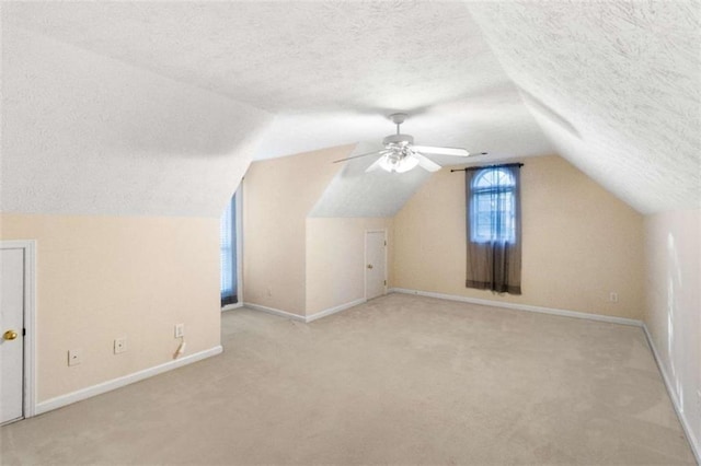 additional living space featuring light carpet, a textured ceiling, vaulted ceiling, and ceiling fan