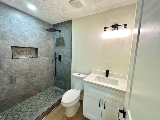 850 Greenhedge Dr, Stone Mountain, GA 30088 - bathroom featuring wood finished floors, a tile shower, a textured ceiling, and vanity