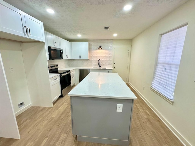 850 Greenhedge Dr, Stone Mountain, GA 30088 - kitchen featuring appliances with stainless steel finishes, a kitchen island, light wood-type flooring, decorative backsplash, and recessed lighting