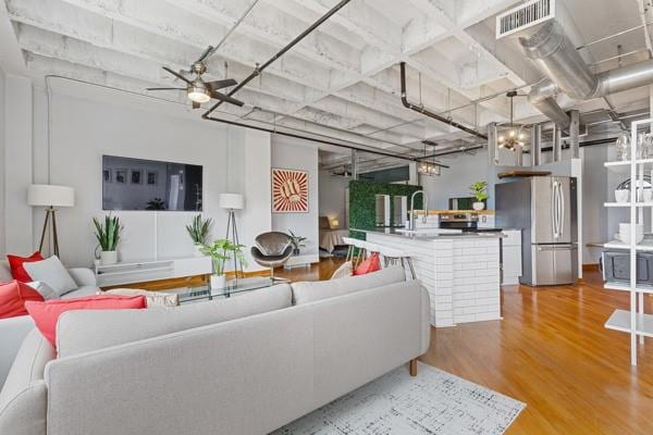 living room featuring wood-type flooring, ceiling fan, and sink