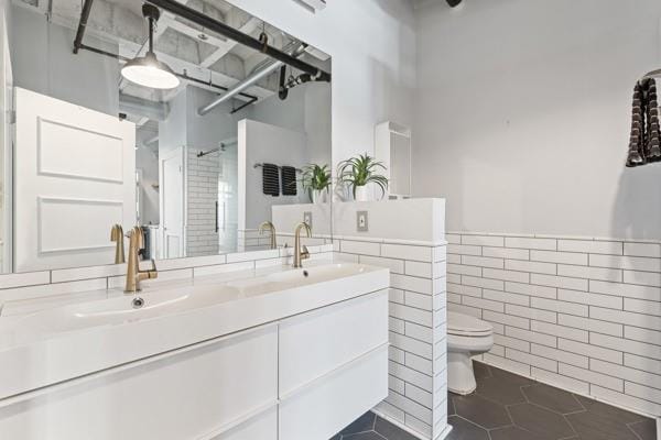 bathroom with tile walls, vanity, walk in shower, toilet, and tile patterned floors