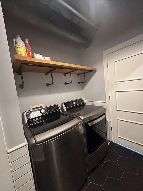 washroom with dark tile patterned floors and washer and clothes dryer