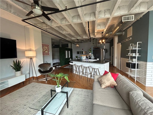 living room featuring wood-type flooring, sink, and ceiling fan