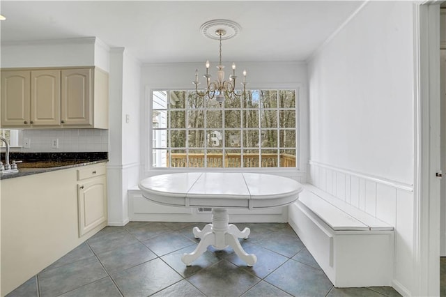 bathroom with tile patterned flooring, breakfast area, a notable chandelier, ornamental molding, and tasteful backsplash