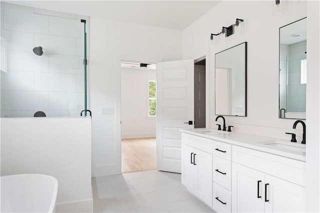 full bath featuring a sink, a freestanding tub, a shower stall, and double vanity