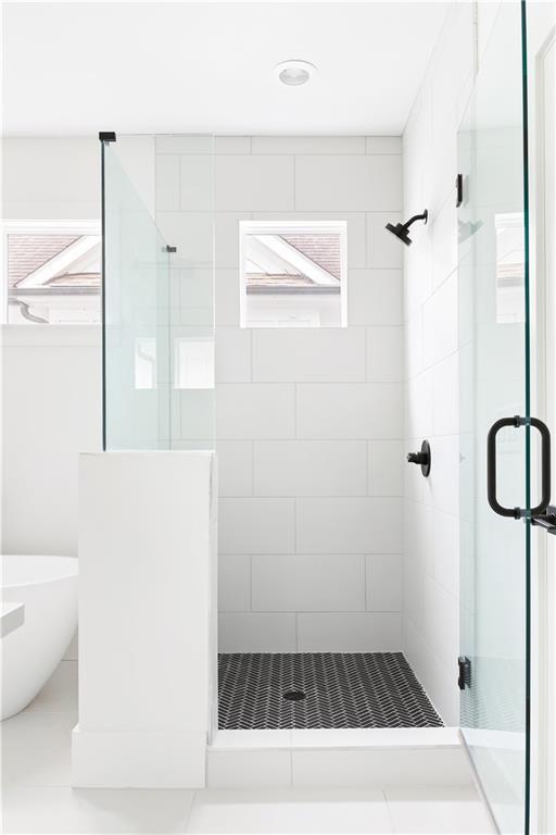full bathroom with a healthy amount of sunlight, a freestanding tub, and a stall shower