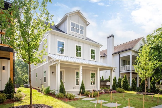view of front of home featuring a standing seam roof, board and batten siding, a front lawn, and metal roof