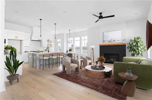 living room with recessed lighting, ceiling fan, a glass covered fireplace, and light wood-style floors