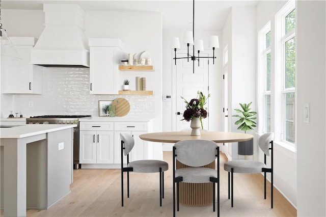 kitchen featuring light wood-style floors, a chandelier, high end range, decorative backsplash, and custom exhaust hood