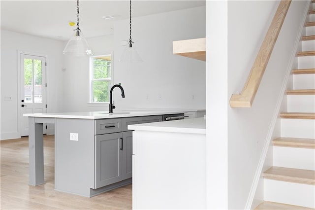 kitchen featuring light wood-style floors, light countertops, pendant lighting, and gray cabinetry
