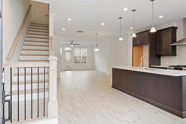 kitchen featuring decorative backsplash, dark brown cabinetry, ceiling fan, sink, and light hardwood / wood-style flooring