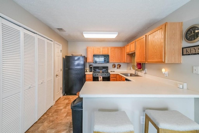 kitchen with sink, black appliances, a kitchen breakfast bar, and kitchen peninsula