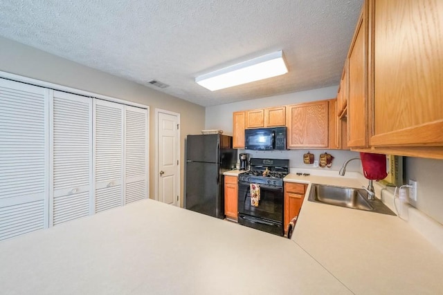 kitchen with sink, black appliances, and a textured ceiling