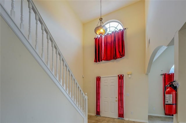 foyer featuring baseboards, a high ceiling, and stairs