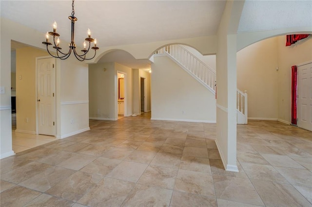 interior space with a chandelier, arched walkways, stairway, and baseboards