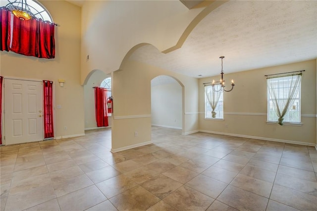 tiled foyer with an inviting chandelier, baseboards, arched walkways, and a textured ceiling