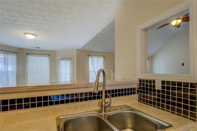 kitchen with a textured ceiling, visible vents, decorative backsplash, and a sink